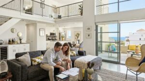 Pareja De Inversores Revisando Documentos De Compra De Una Vivienda Turistica En Un Salon Moderno Con Vistas Al Mar En La Costa Del Sol